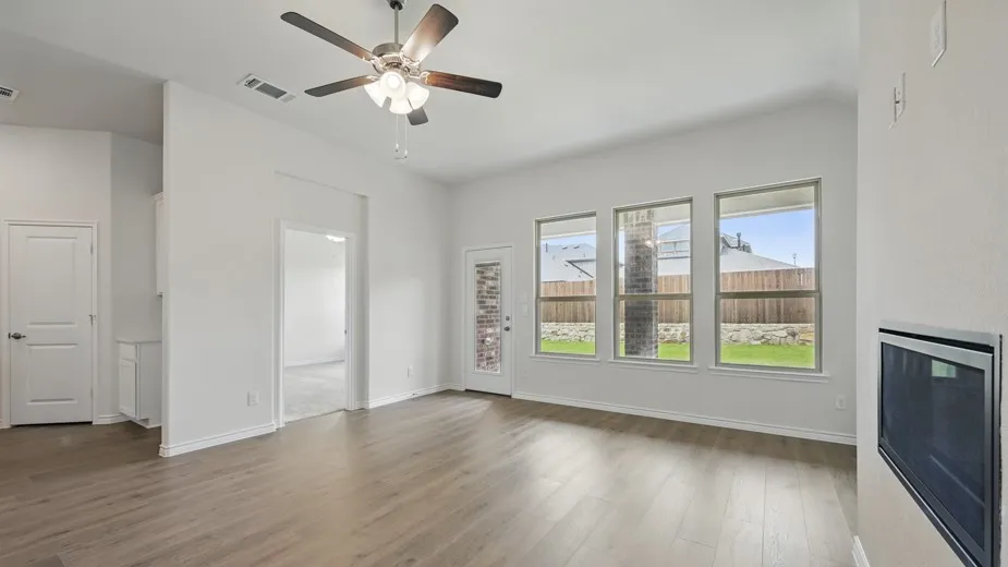 Spacious living area featuring wood-finish flooring, a ceiling fan, and an integrated fireplace
