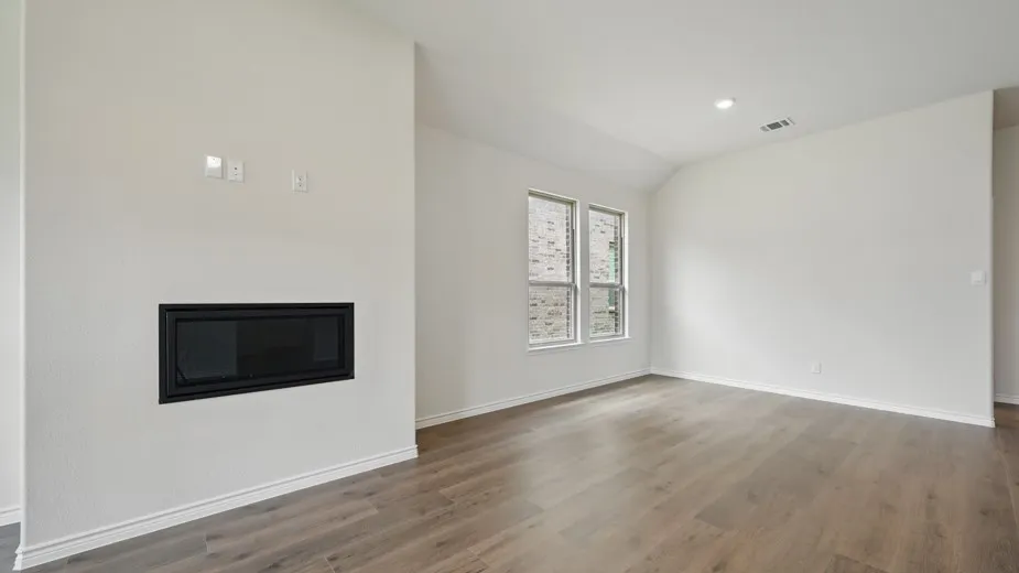 Living area featuring an integrated linear fireplace, wood-finish flooring, recessed lighting, and two windows
