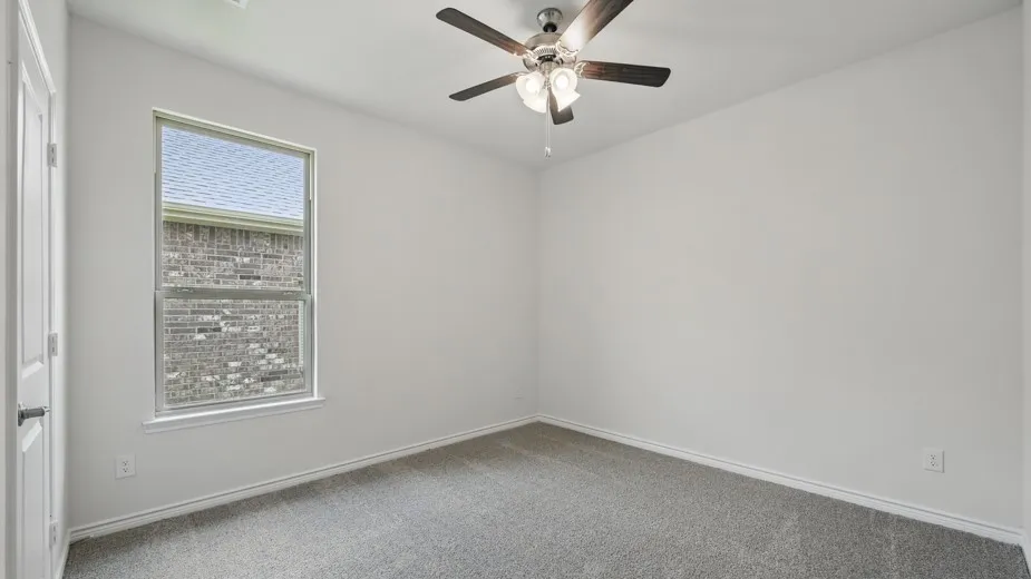 Carpeted room featuring a single window with a white frame, white walls, and a ceiling fan with light fixture