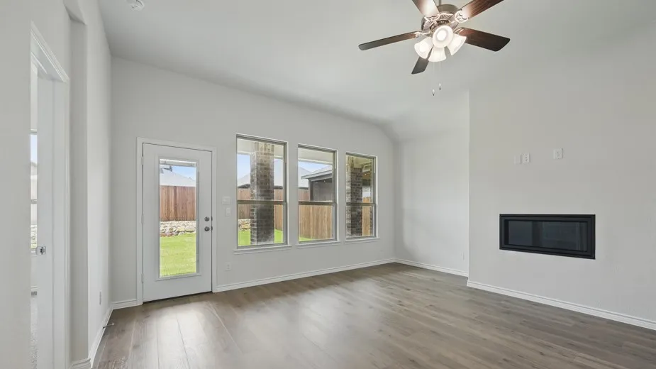 Living area featuring wood-finish flooring, a wall-mounted linear fireplace, and an angled ceiling with a ceiling fan