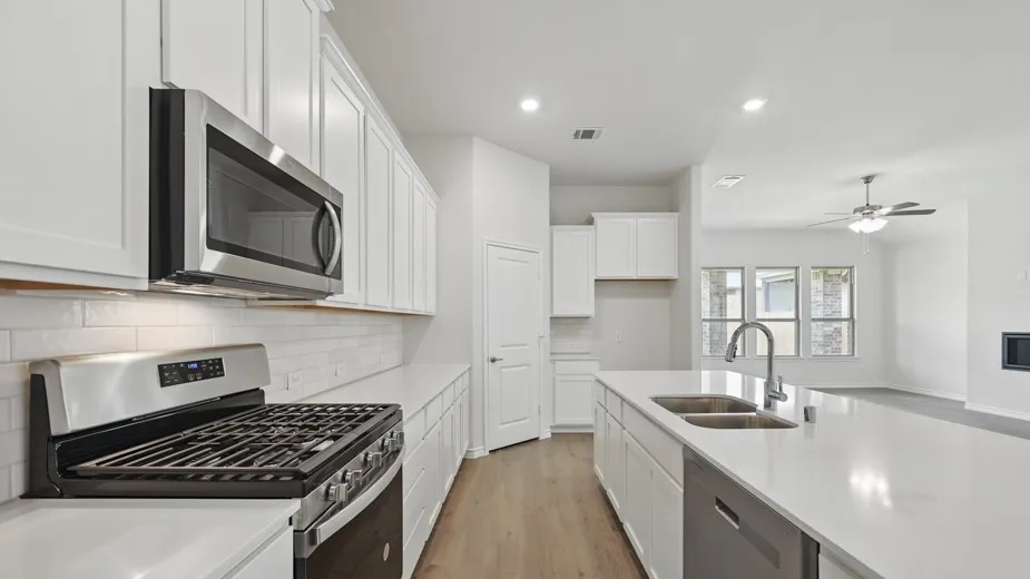 Contemporary kitchen featuring white shaker cabinetry, stainless steel appliances, a subway tile backsplash, and an extended island with dual sinks