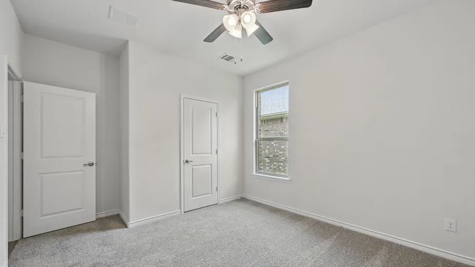 Neutral-toned bedroom featuring plush gray carpeting, white painted walls, and a contemporary ceiling fan with integrated lighting