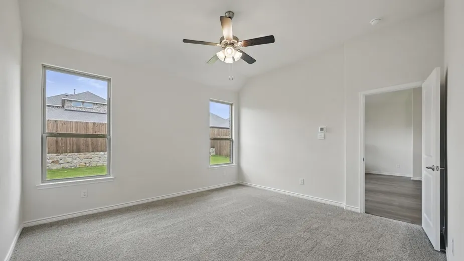 Spacious bedroom featuring light grey carpeting, white walls, and a vaulted ceiling