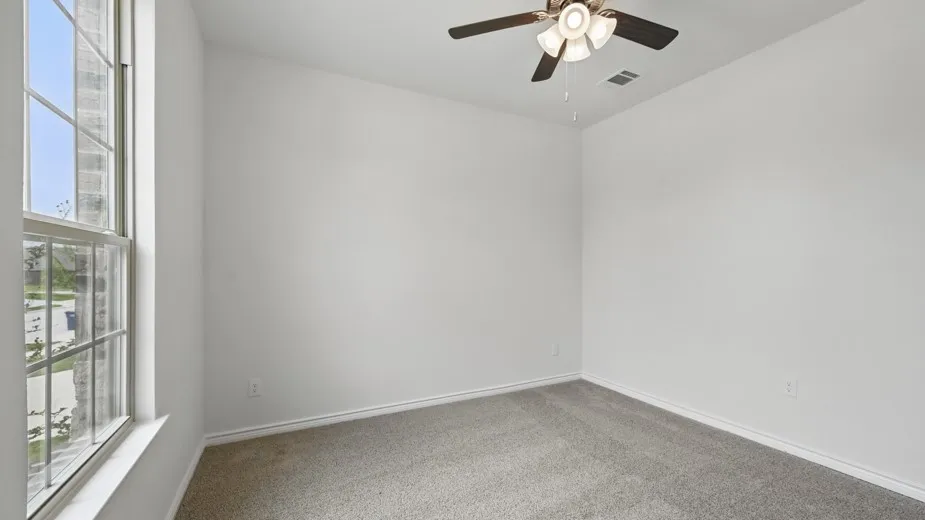Carpeted room featuring a double-hung window, white baseboards, and a ceiling fan with integrated lighting