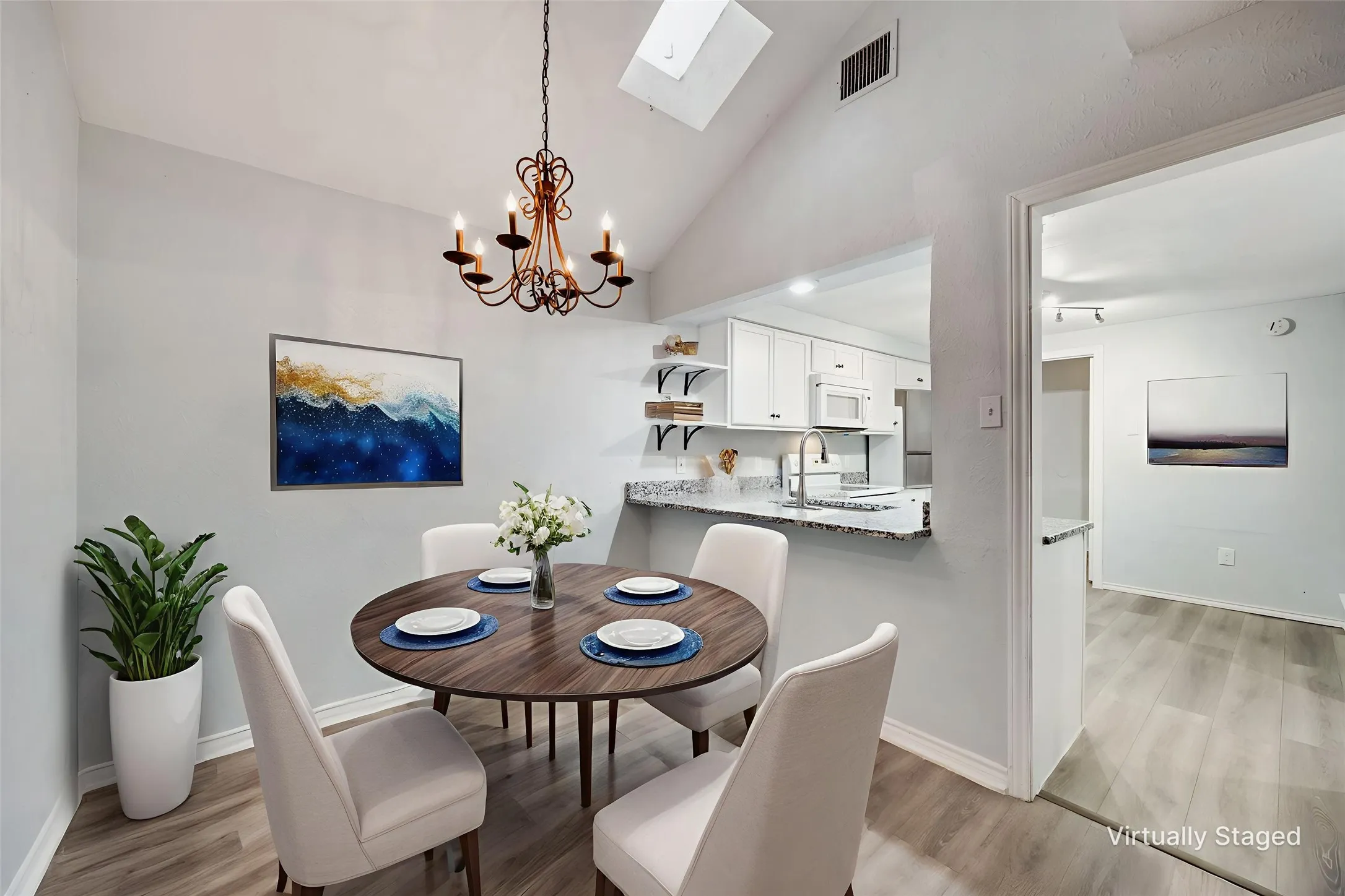 Dining area featuring a vaulted ceiling with a skylight and a decorative chandelier