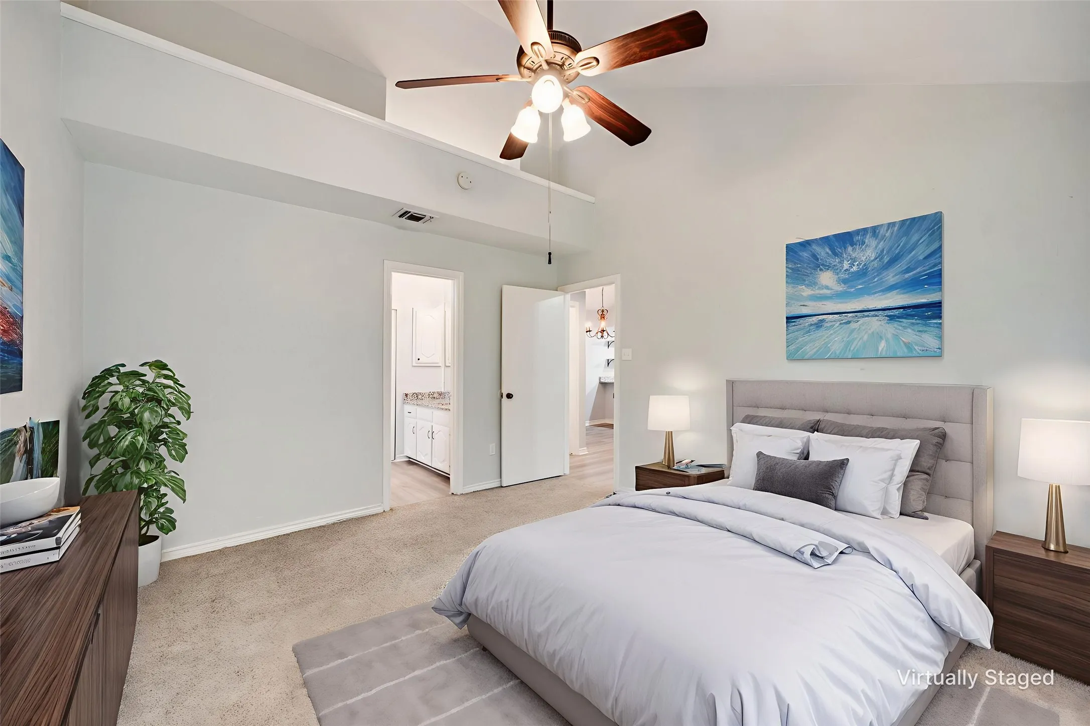 Vaulted ceiling bedroom featuring a ceiling fan with light fixture, carpet flooring, and white baseboards