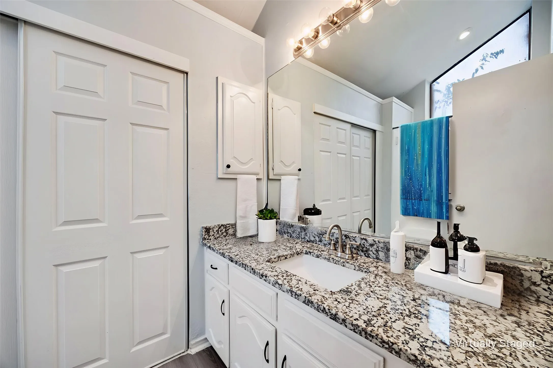Bathroom vanity featuring a speckled countertop, undermount sink with a brushed nickel faucet, and white cabinetry