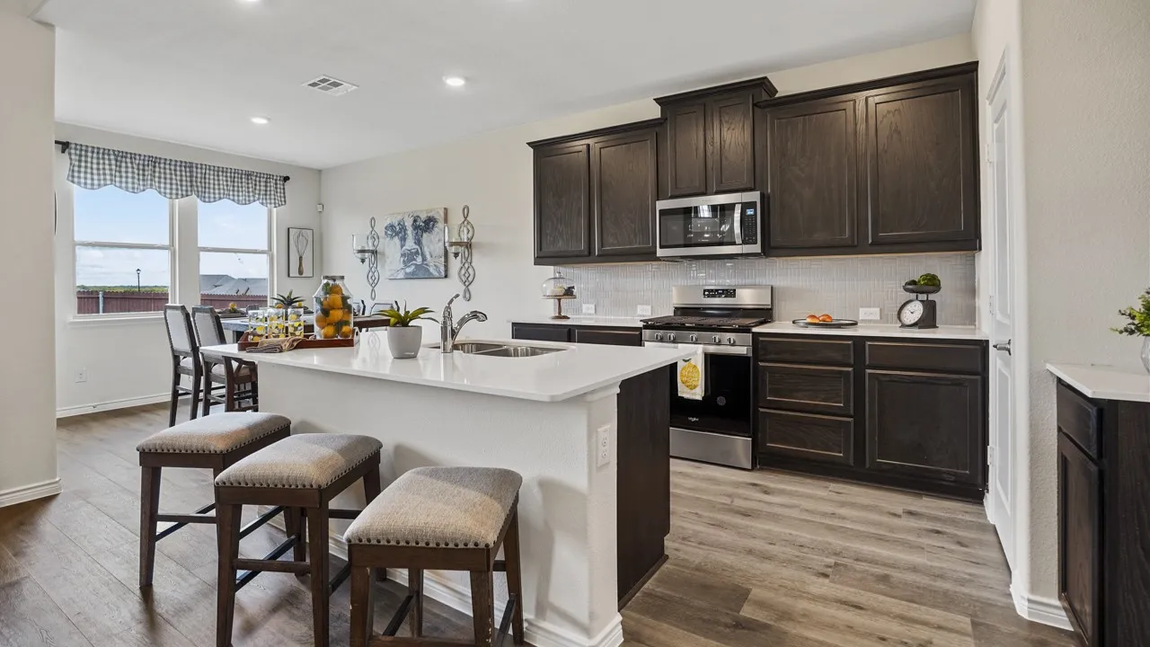 Kitchen featuring an island with countertop seating, dark wood cabinetry, white countertops, stainless steel appliances, and wood-finish flooring