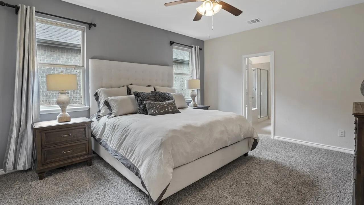 Carpeted room featuring a ceiling fan with integrated lighting, a neutral color palette, and an open doorway revealing a shower enclosure