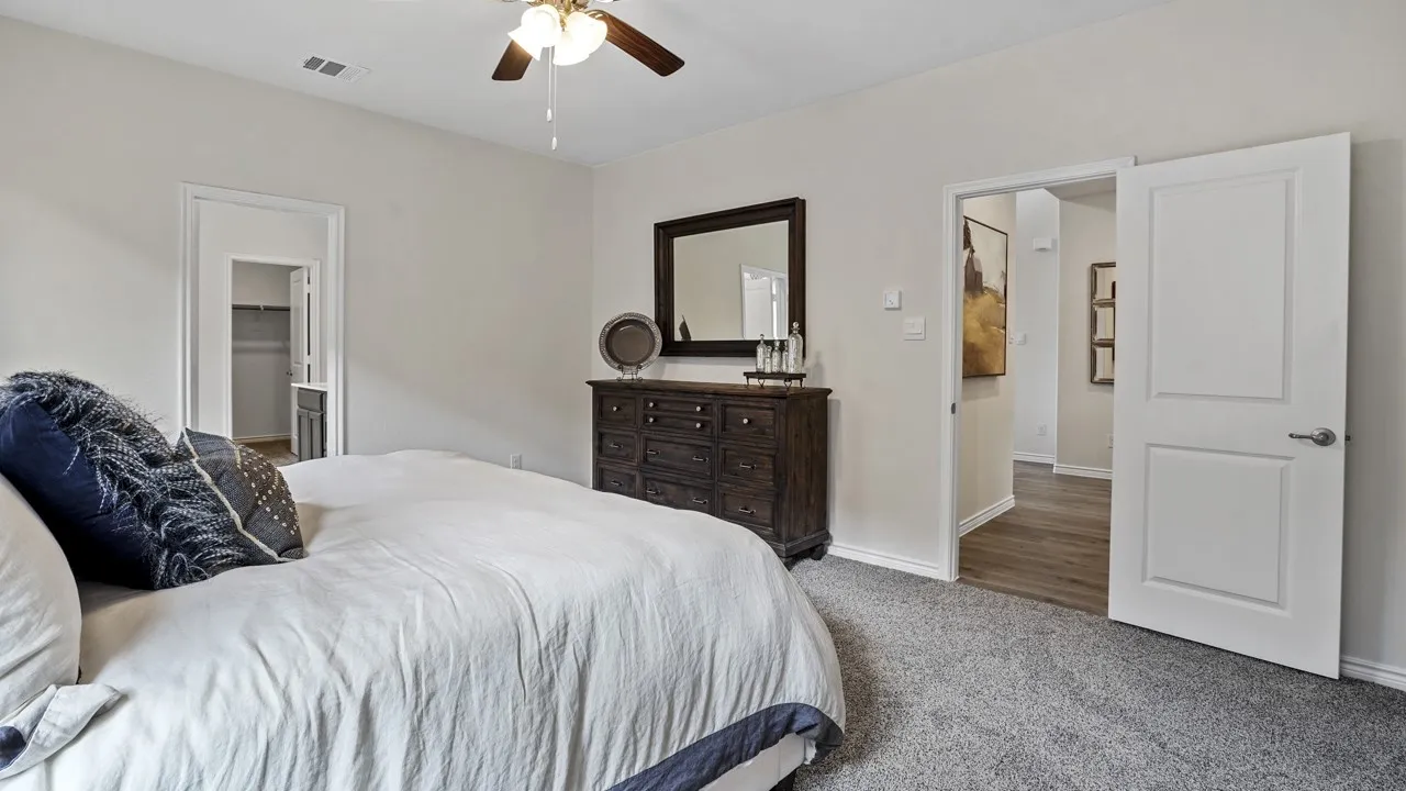 Carpeted bedroom with a ceiling fan, white paneled doors, and light neutral wall colors