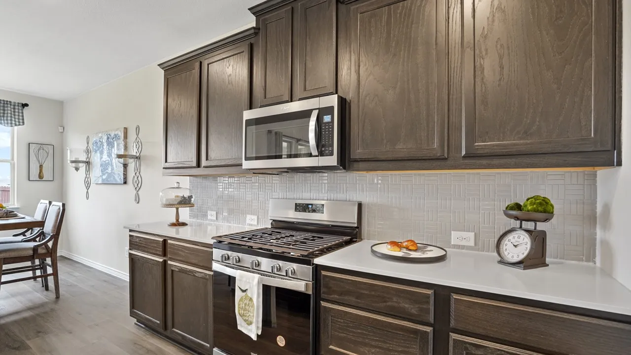 Kitchen featuring dark wood-finish cabinetry, light countertops, stainless steel appliances, a gas range, and a tiled backsplash