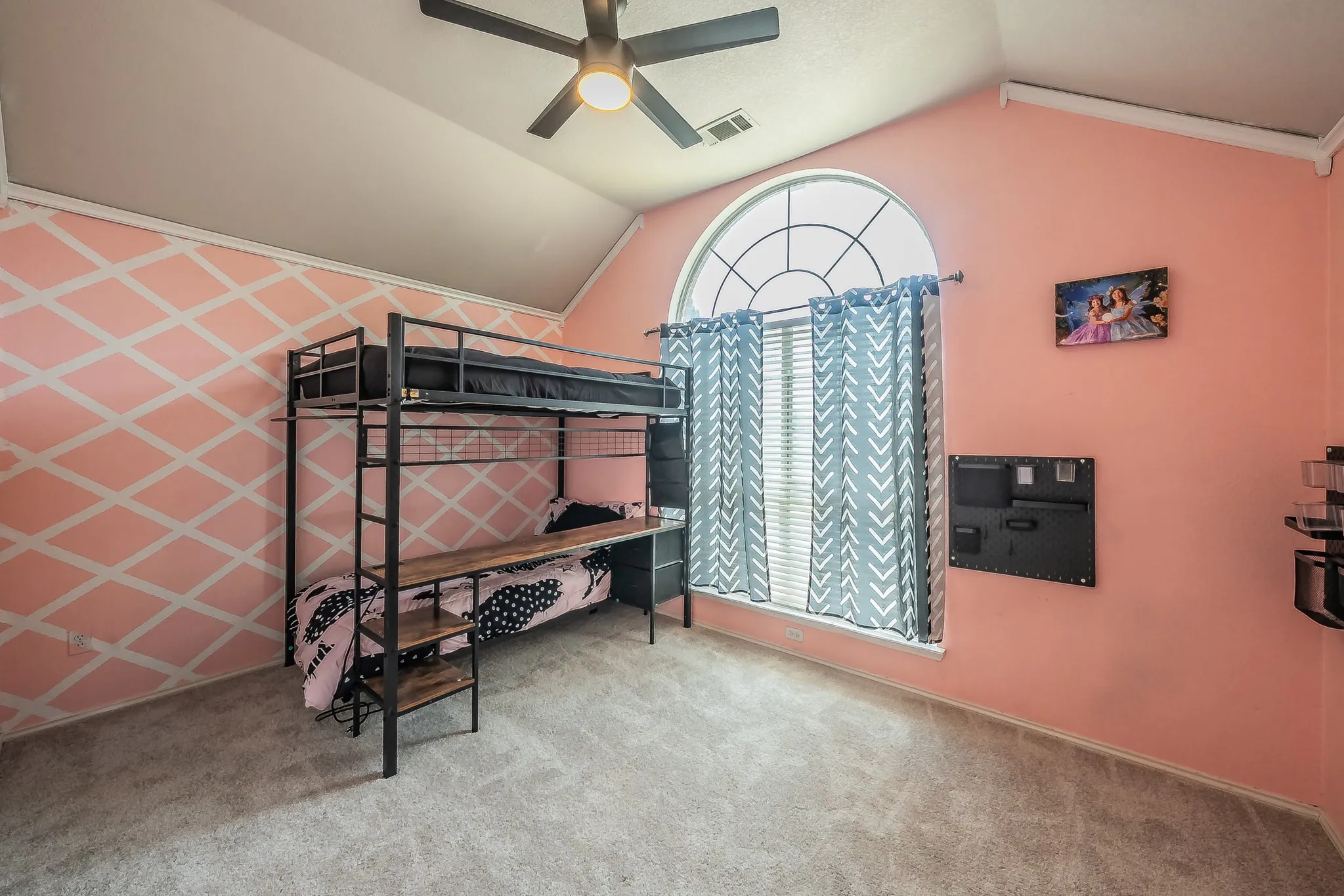 Room featuring a vaulted ceiling, a large arched window with grid detailing, and light-colored carpeting