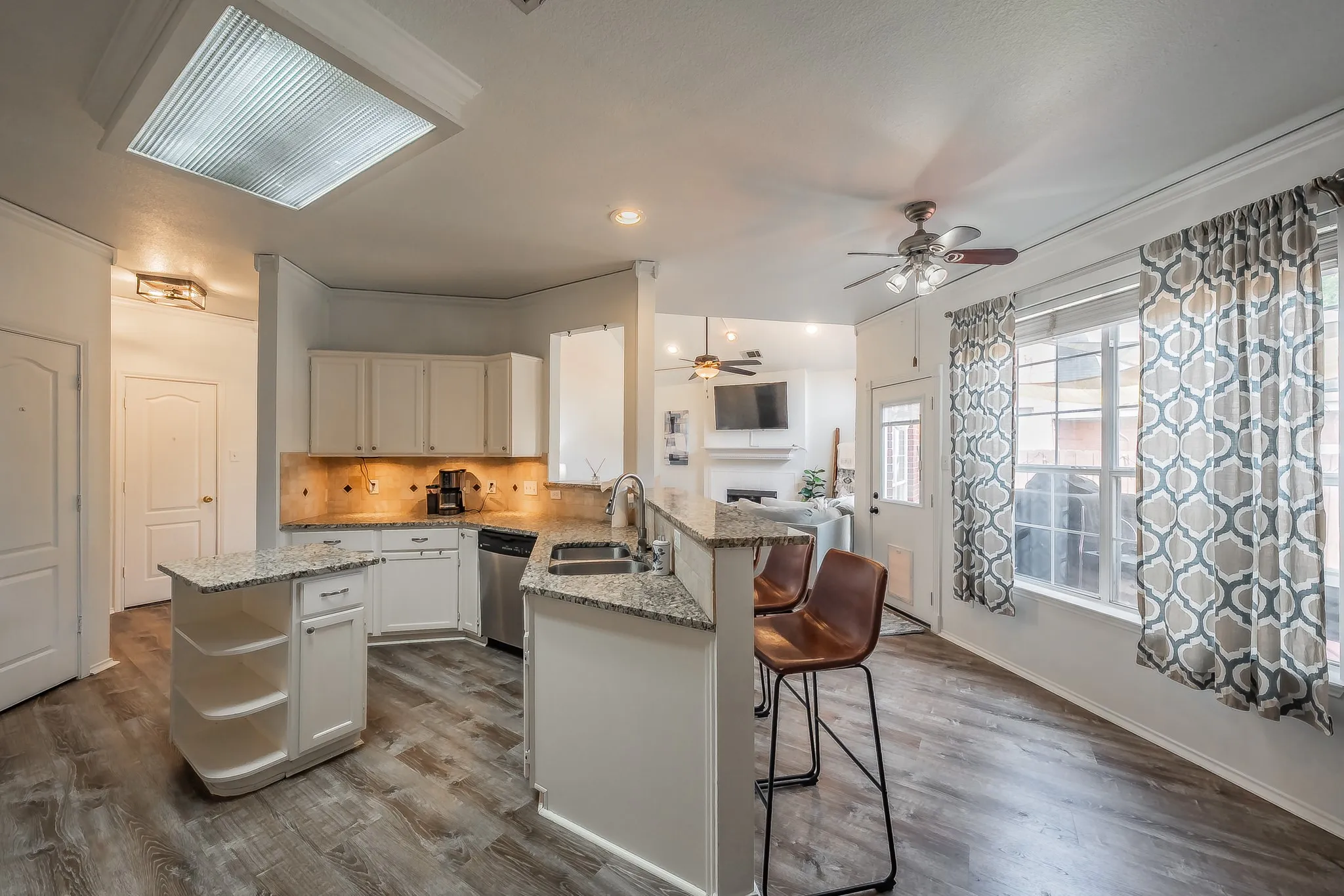 Kitchen featuring light wood-finish flooring, white cabinetry, and granite countertops