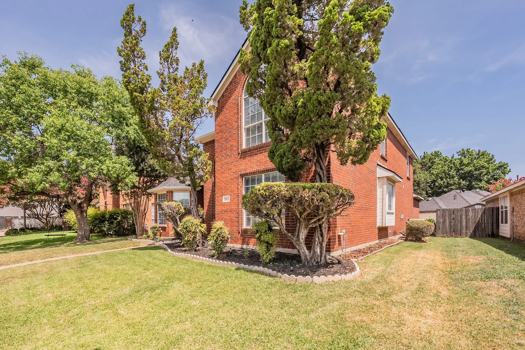 Brick exterior featuring an arched window and a bay window