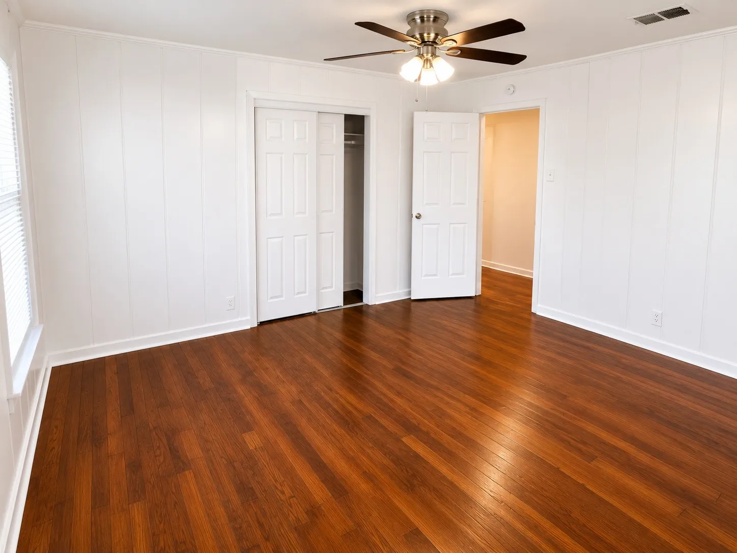 Room featuring wood-finish flooring, white paneled walls, and white baseboards