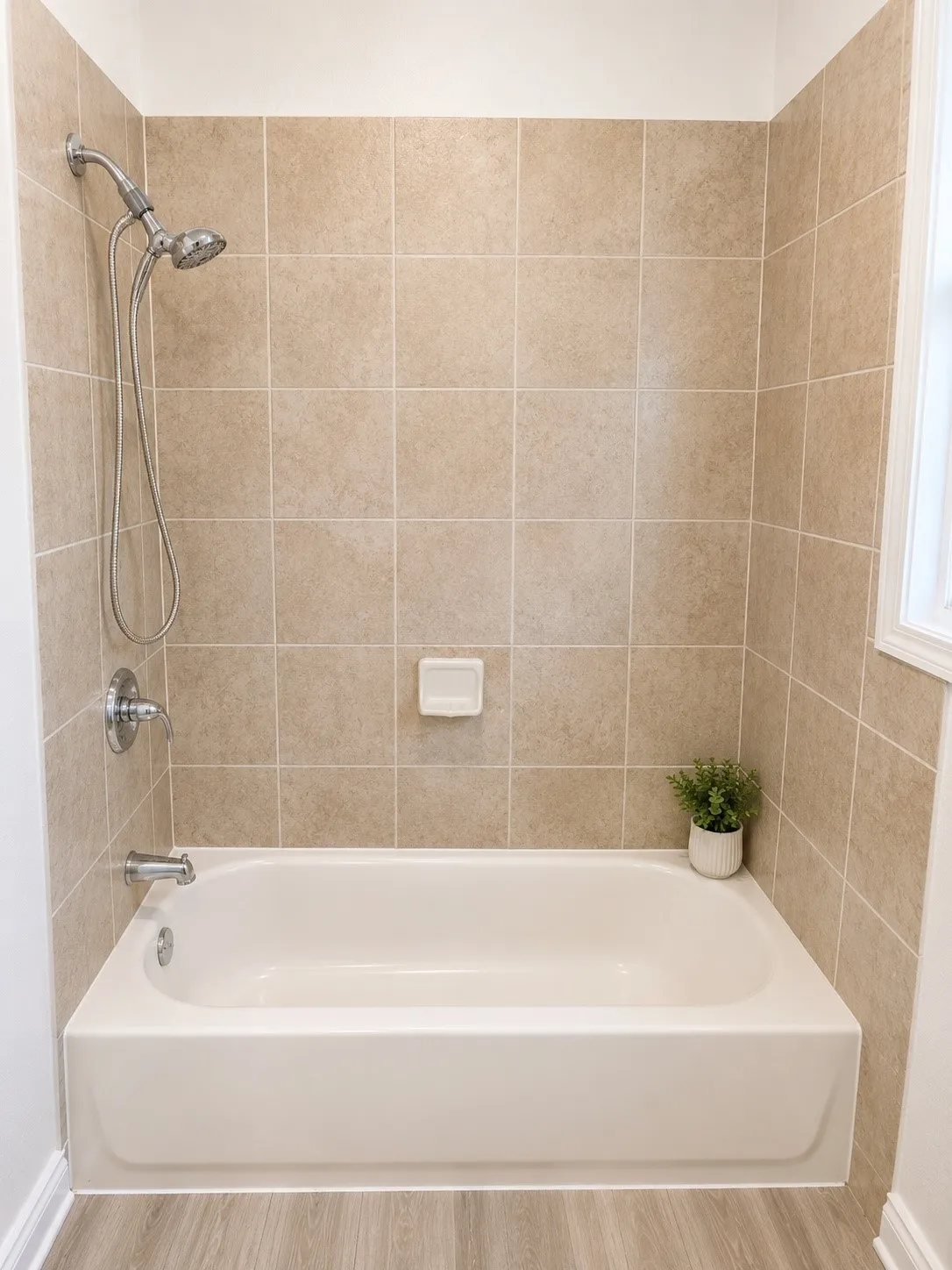 Bathtub with subway tile surround, chrome fixtures, and a hand-held shower head