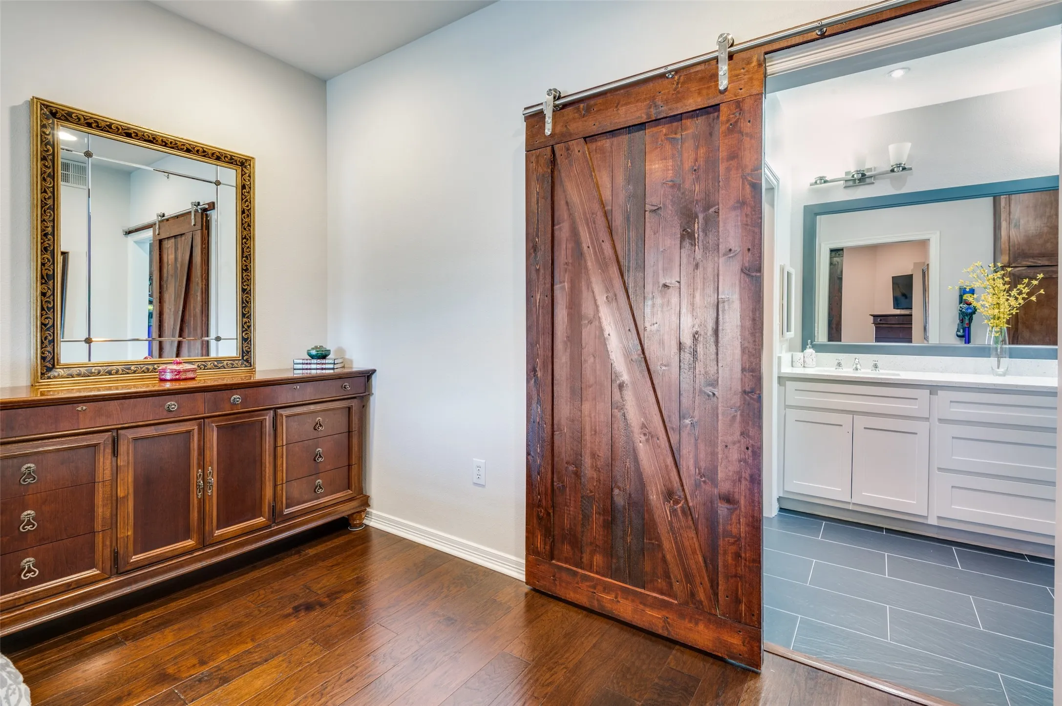 Barn door separating primary bedroom and ensuite primary bathroom