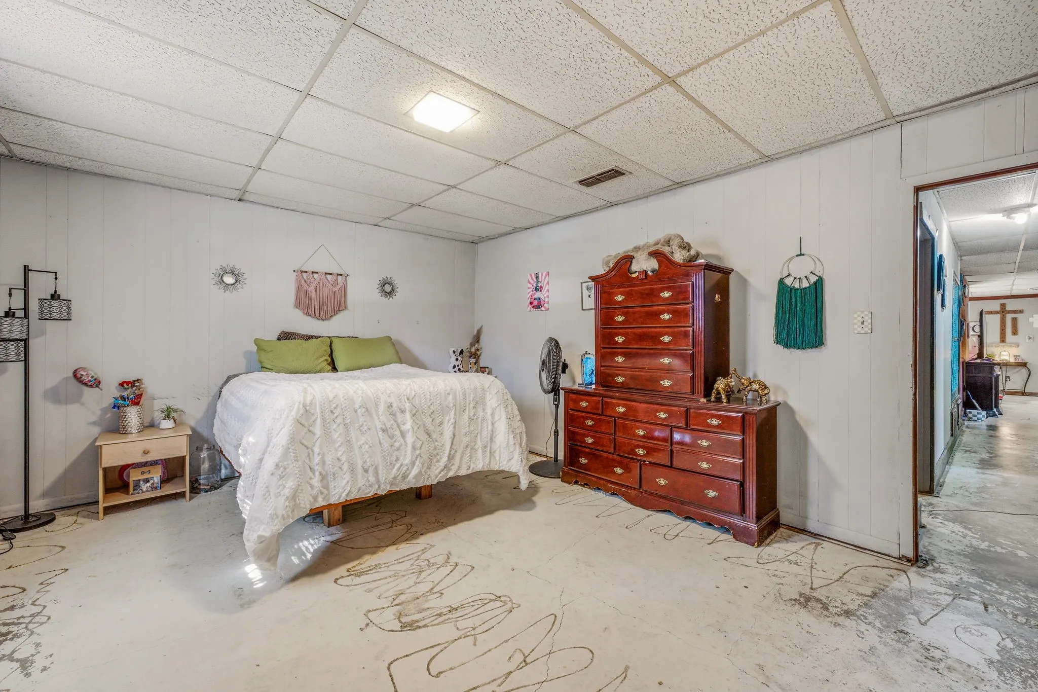 Spacious room featuring light-colored panel walls and a drop ceiling