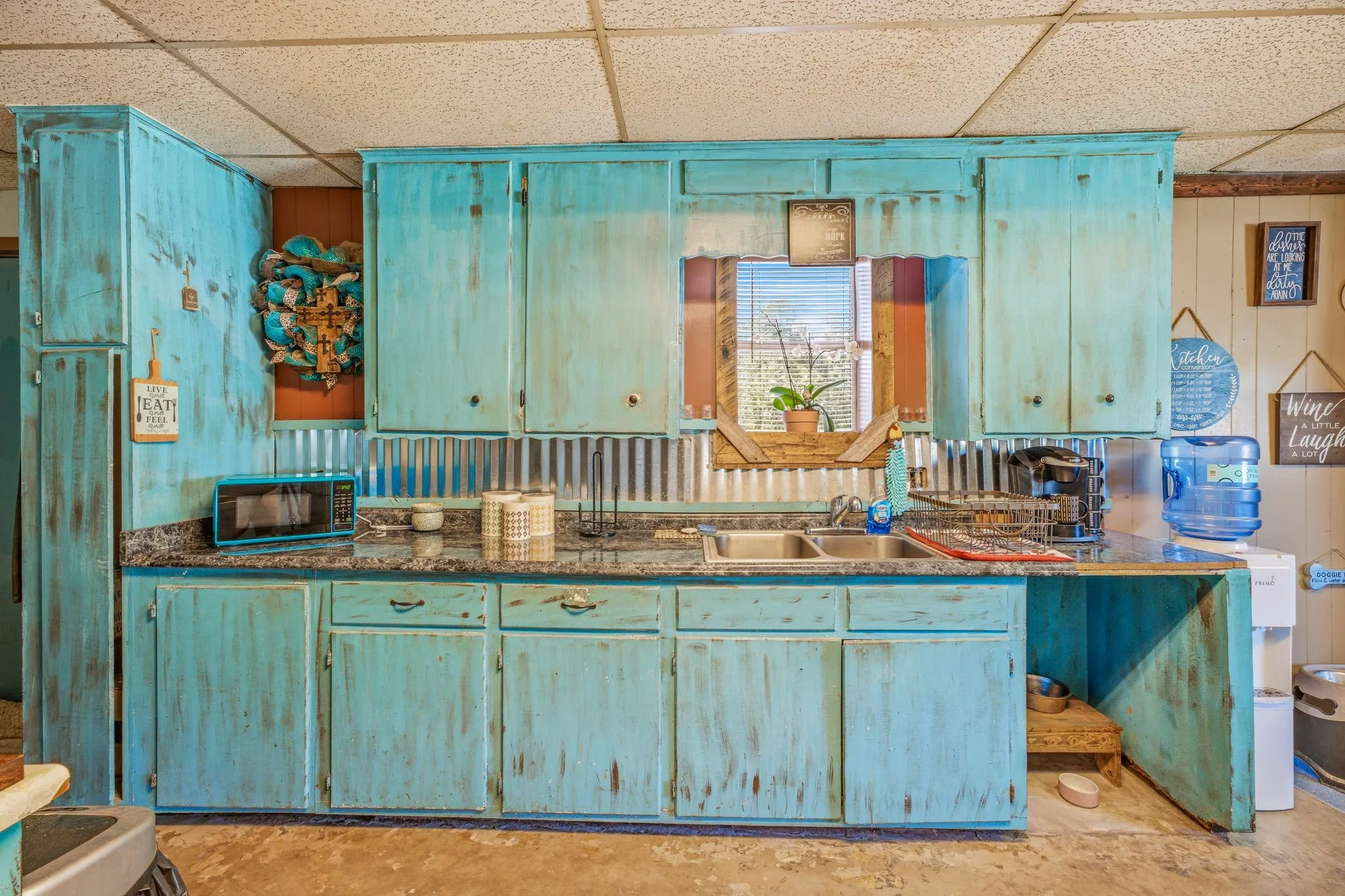 Kitchen featuring distressed turquoise cabinetry and dark countertops