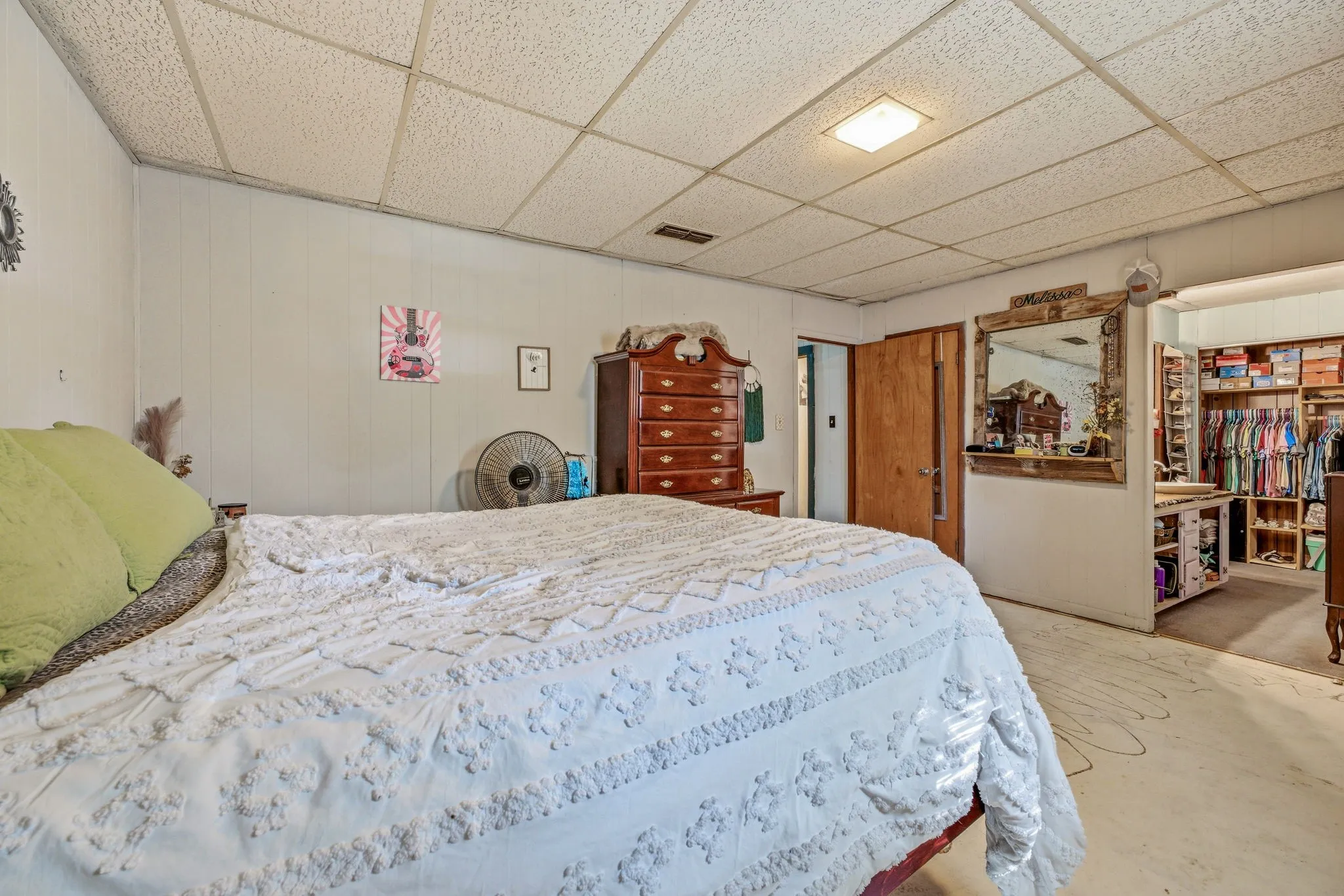 Room featuring wood paneling, a drop ceiling with recessed lighting, an interior wood door, and an open closet with built-in shelving
