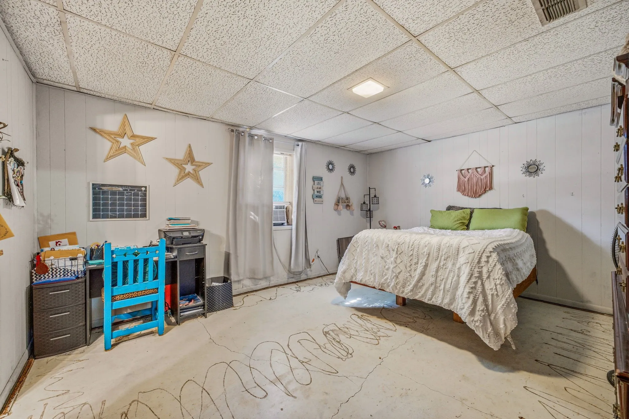 Room featuring white beadboard wall paneling, a drop ceiling with recessed lighting, and a visible window unit