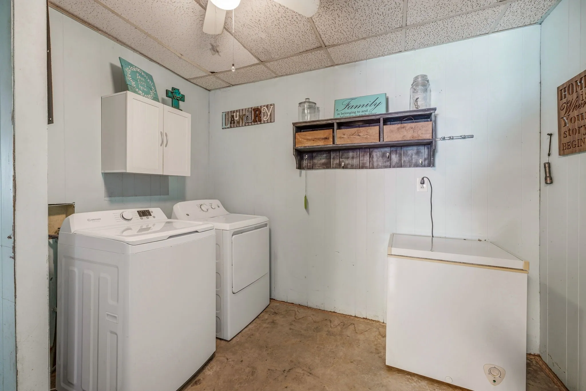 Laundry area featuring white wall cabinetry, a ceiling fan, and light blue wall paneling