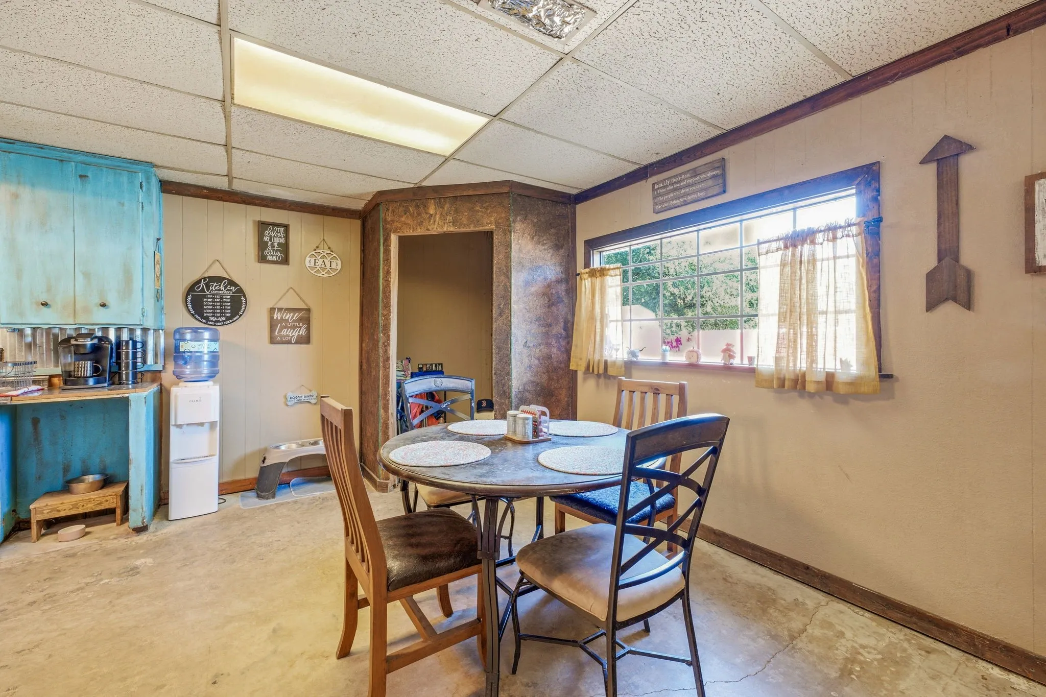 Dining area featuring a fixed window, drop ceiling, and wood-paneled walls with decorative trim