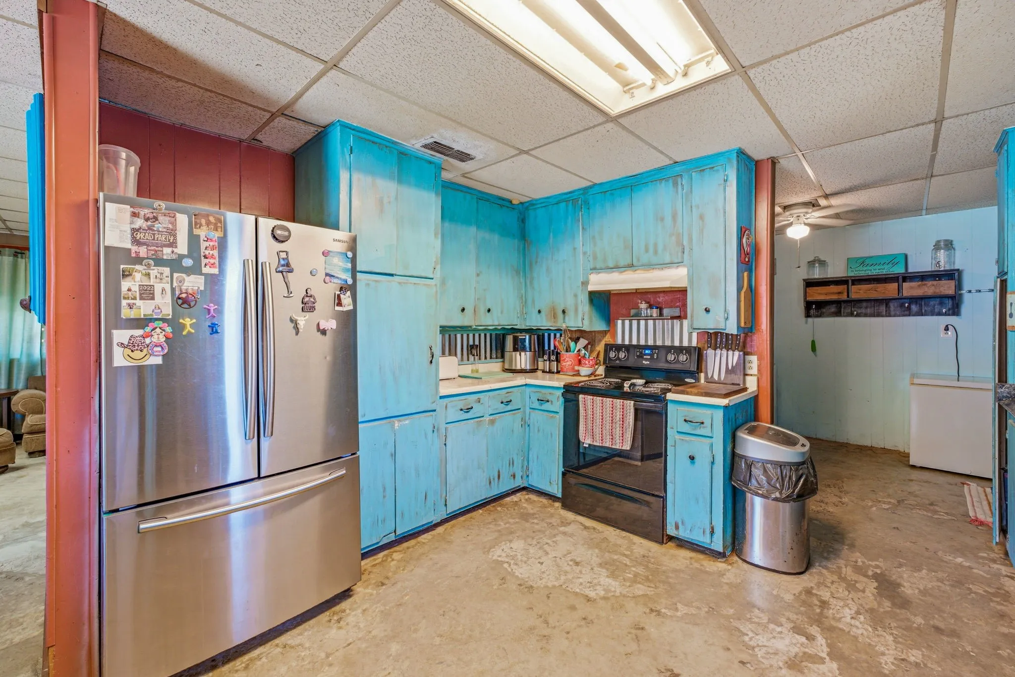 Corner kitchen area featuring painted blue cabinetry, white countertops, built-in shelving, and a black range