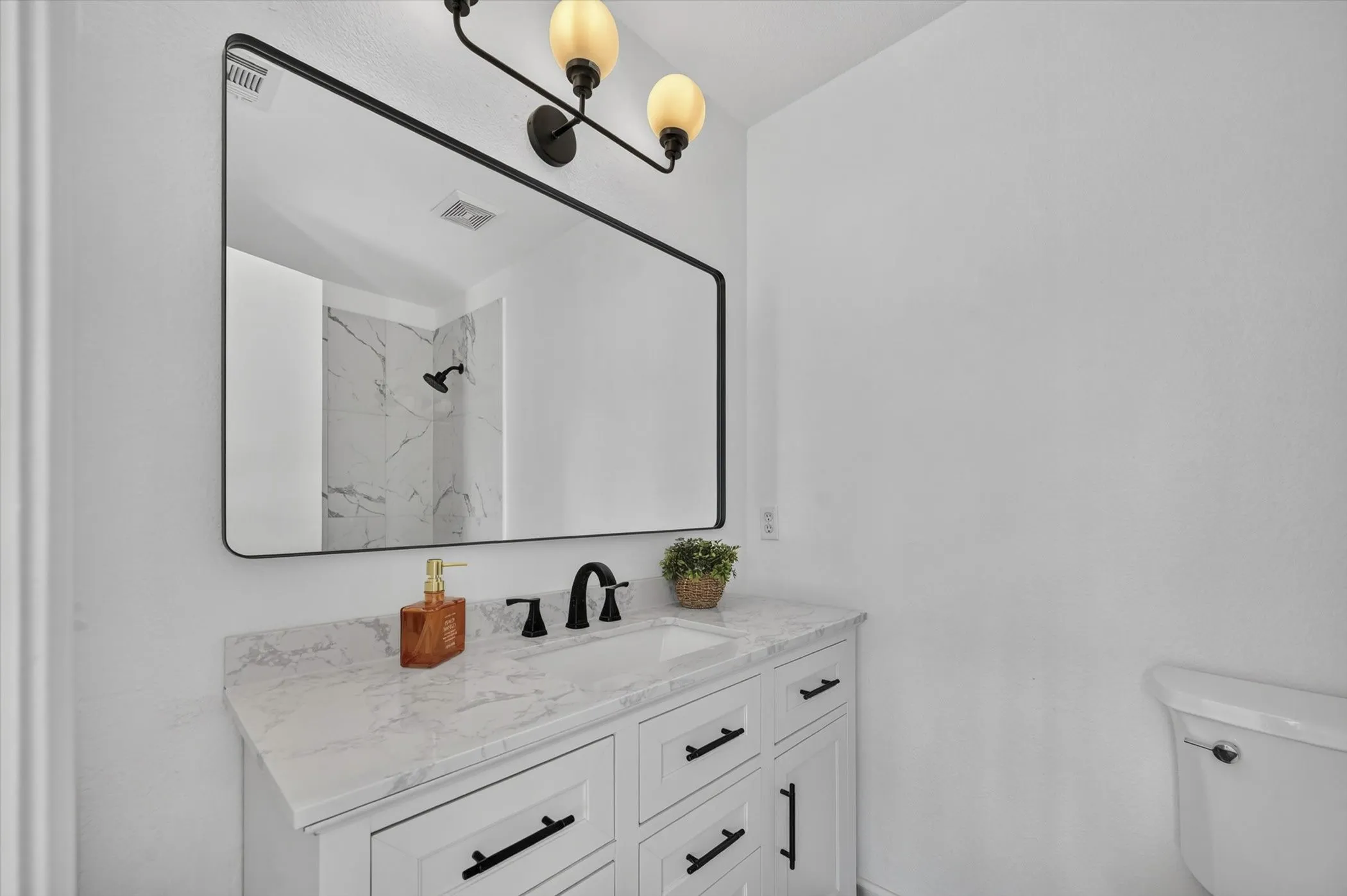 Vanity with a white countertop featuring an undermount sink and matte black faucet