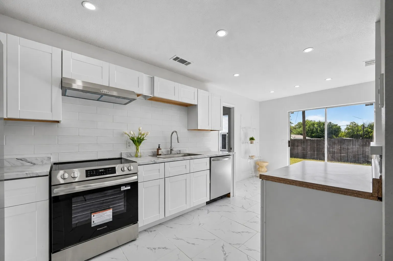 Modern kitchen featuring white shaker cabinetry, stainless steel appliances, marble-look countertops, subway tile backsplash, and recessed​​‌​​​​‌​​‌‌​‌‌​​​‌‌​‌​‌​‌​​​‌​​ lighting