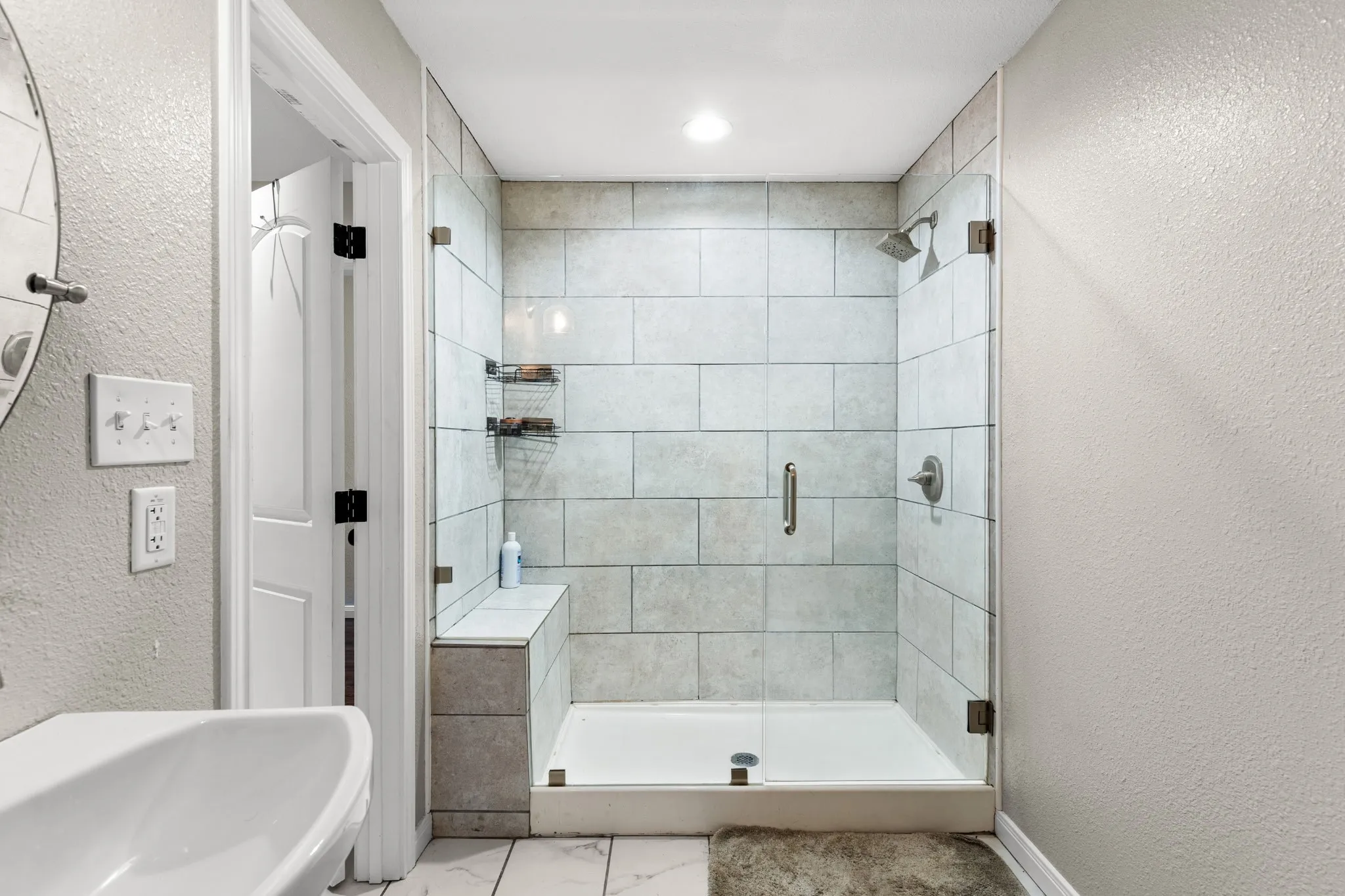 Contemporary shower enclosure featuring glass panels and a built-in bench