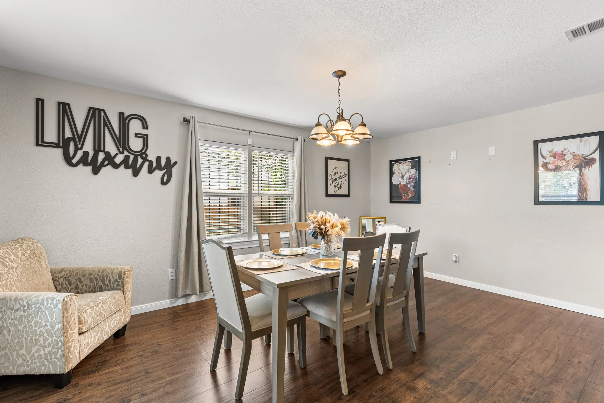 Dining area featuring wood-finish flooring, neutral wall tones, and a multi-bulb chandelier