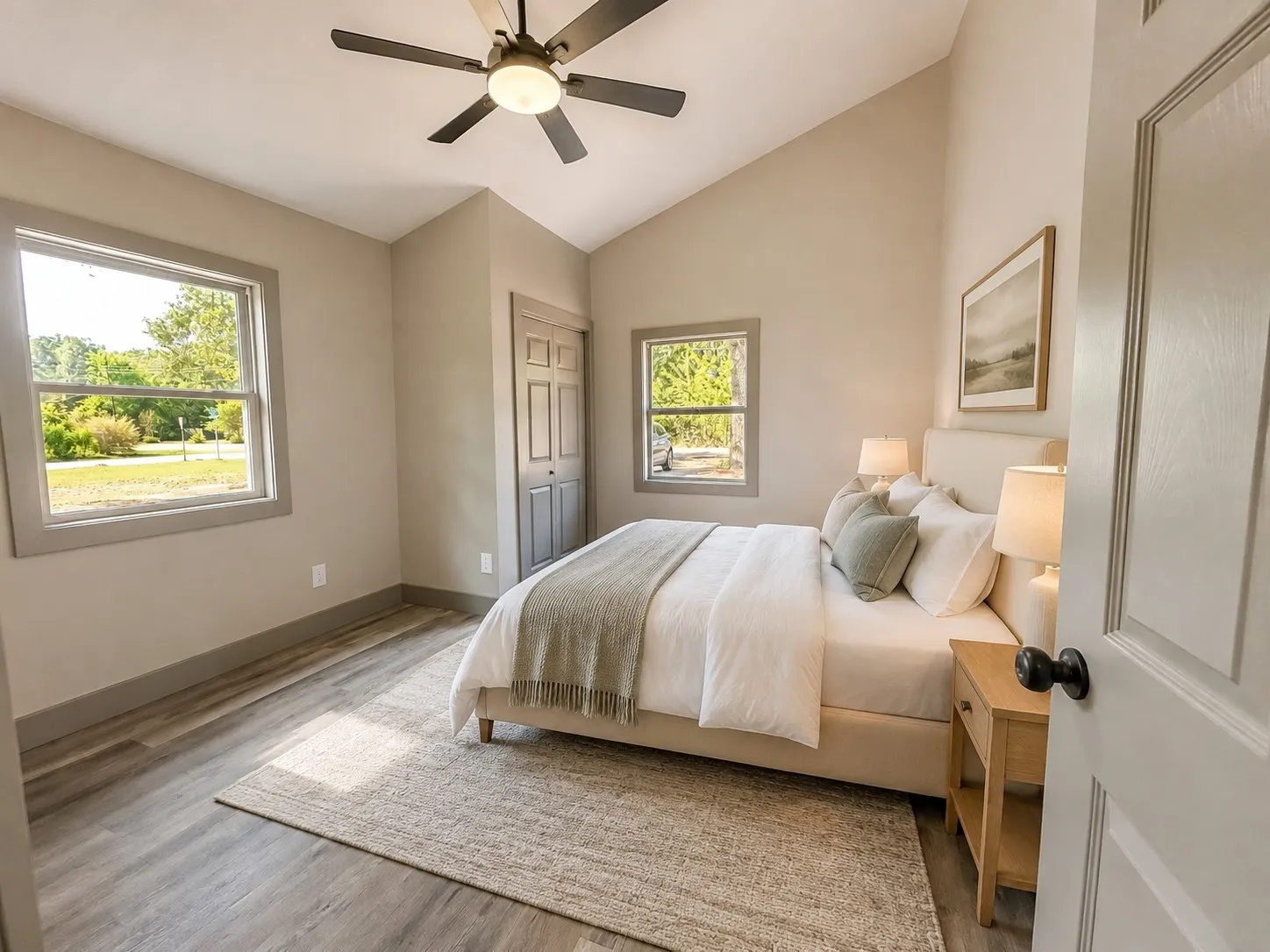 Vaulted ceiling with a ceiling fan, dual windows, wood-finish flooring, and a bi-fold closet door
