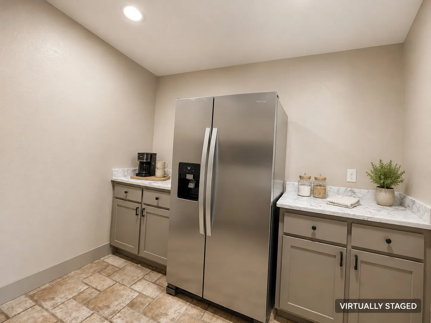 Stainless steel side-by-side refrigerator, recessed lighting, stone-look tile flooring, light-toned cabinetry, and solid surface countertops