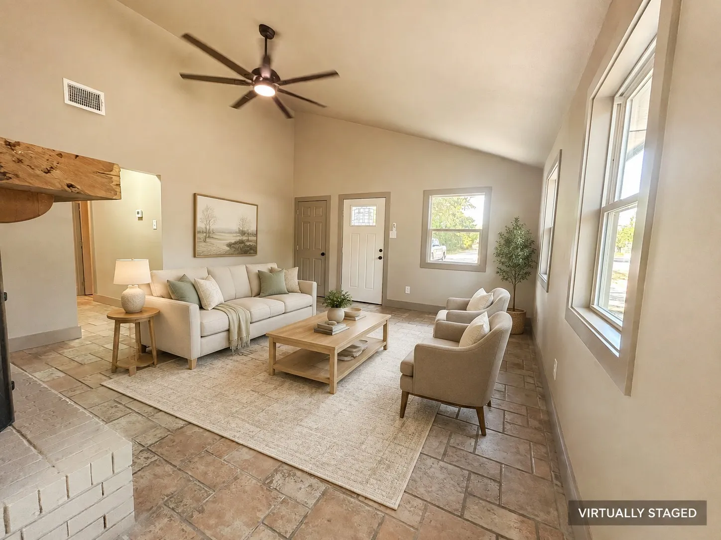 Vaulted ceiling with a contemporary ceiling fan, exposed wood beam, brick fireplace hearth, multiple windows, and patterned tile flooring