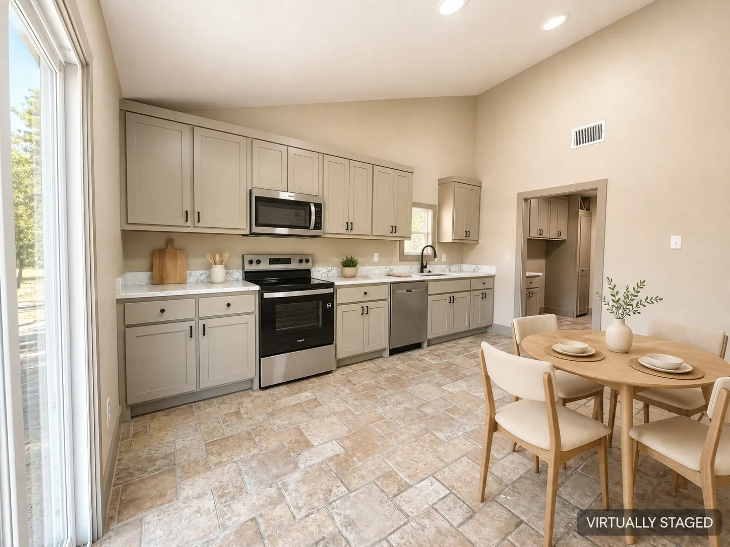 Vaulted ceiling, recessed lighting, tile flooring, stainless steel appliances, and light-toned cabinetry