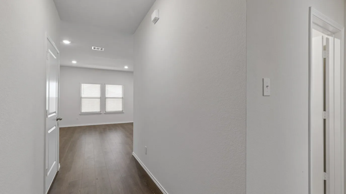 Interior hallway featuring wood-finish flooring, recessed lighting, and a white paneled door