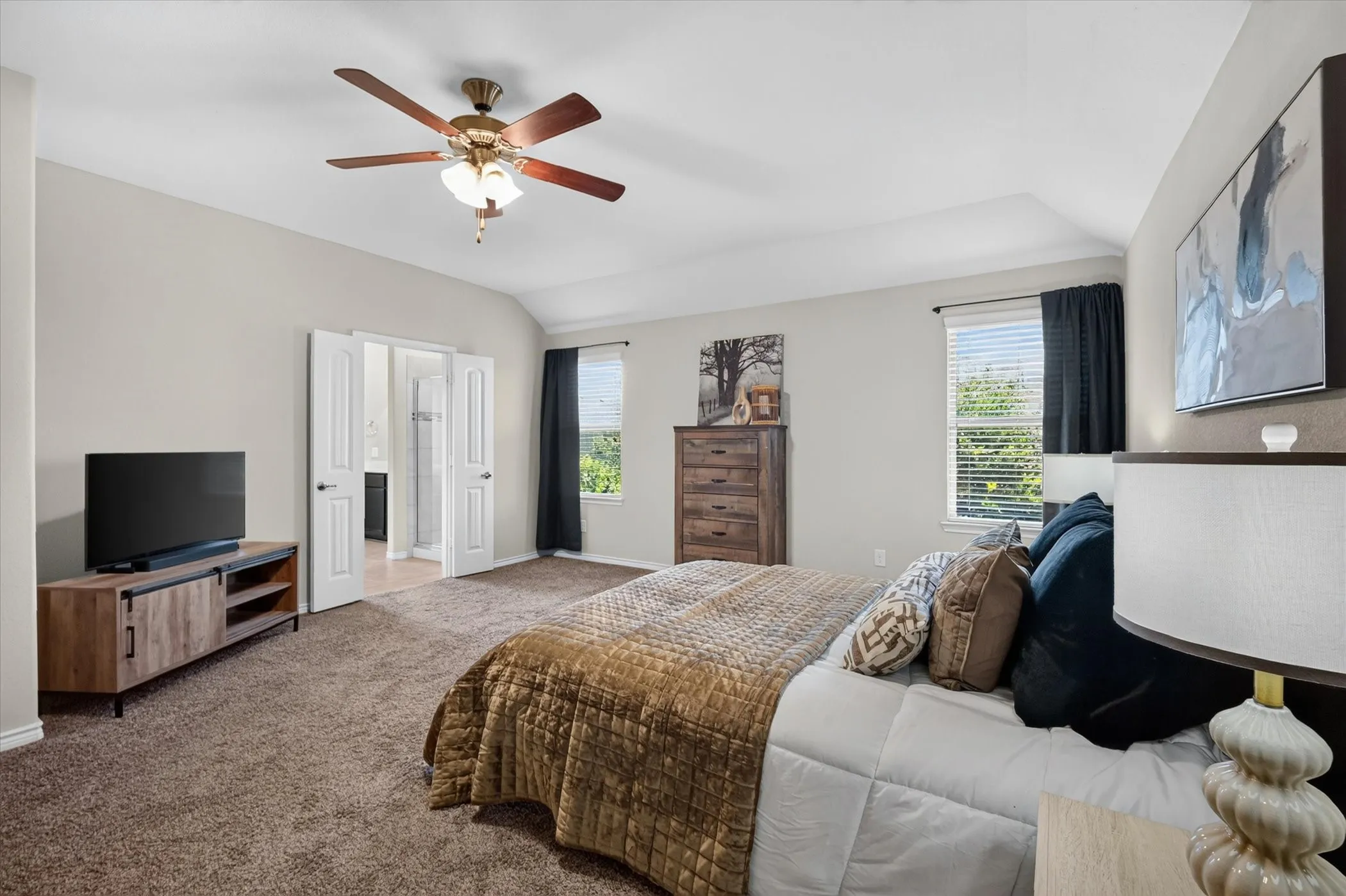 Carpeted room featuring a ceiling fan with integrated lighting, a window with blinds, and double doors opening to an adjoining space