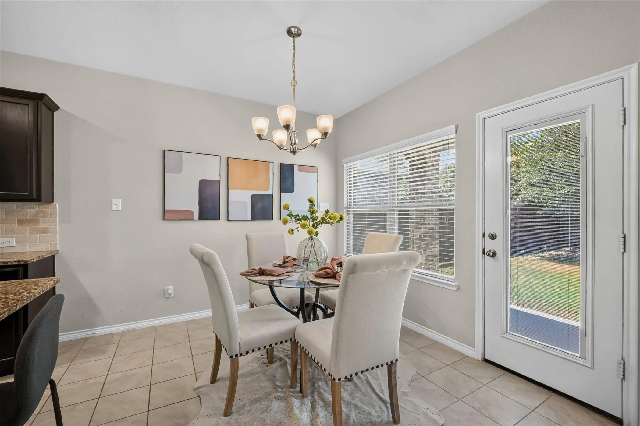 Dining area featuring a contemporary chandelier, tile flooring, and a glass-paneled exterior door