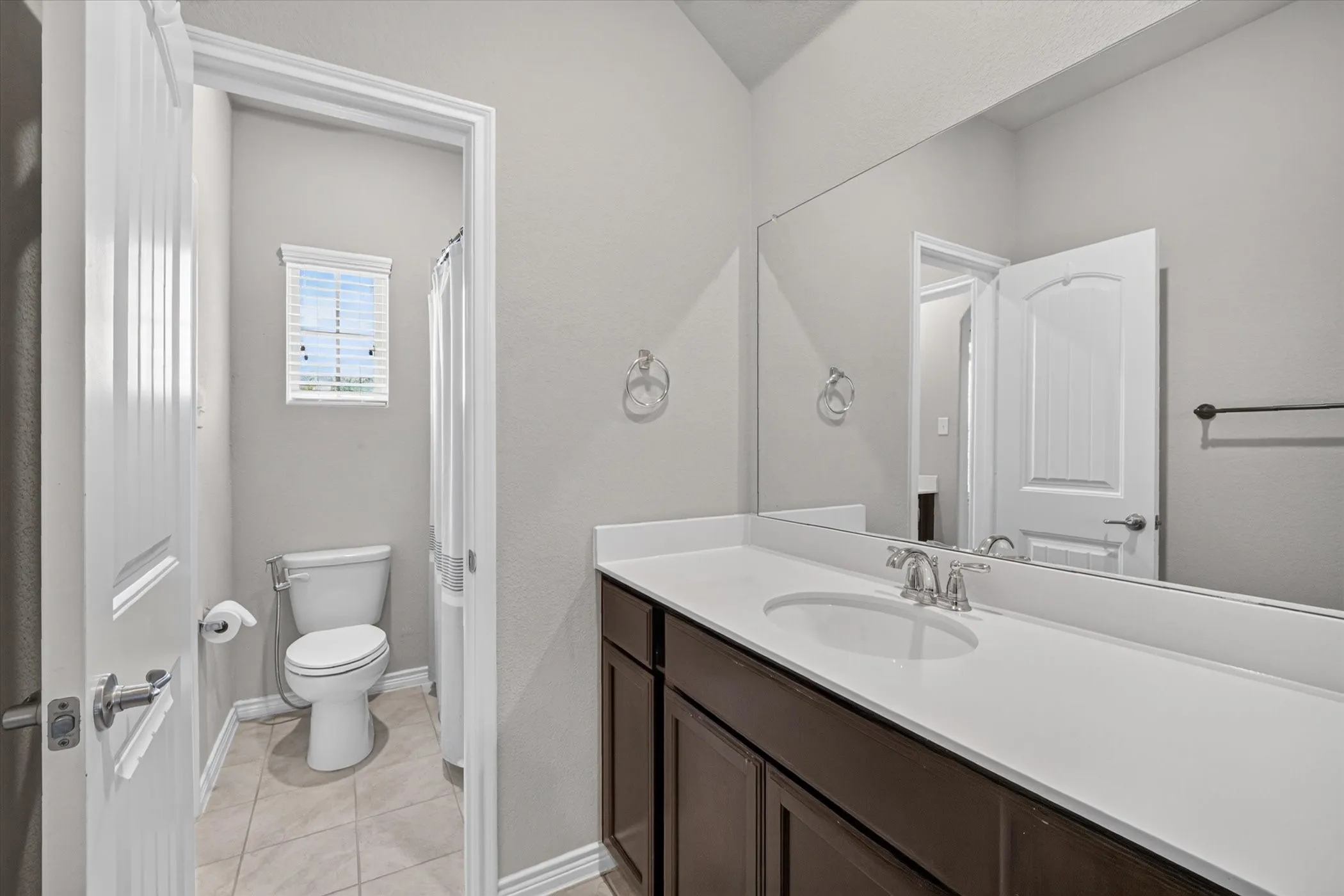 Bathroom featuring a long vanity with dual under-mount sinks, a white countertop, and dark wood-finish cabinetry