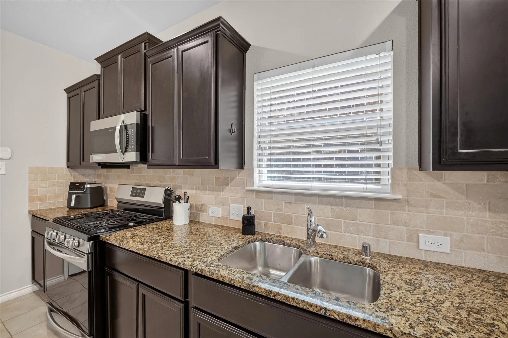 Kitchen featuring dark wood cabinetry, granite countertops, and stainless steel appliances
