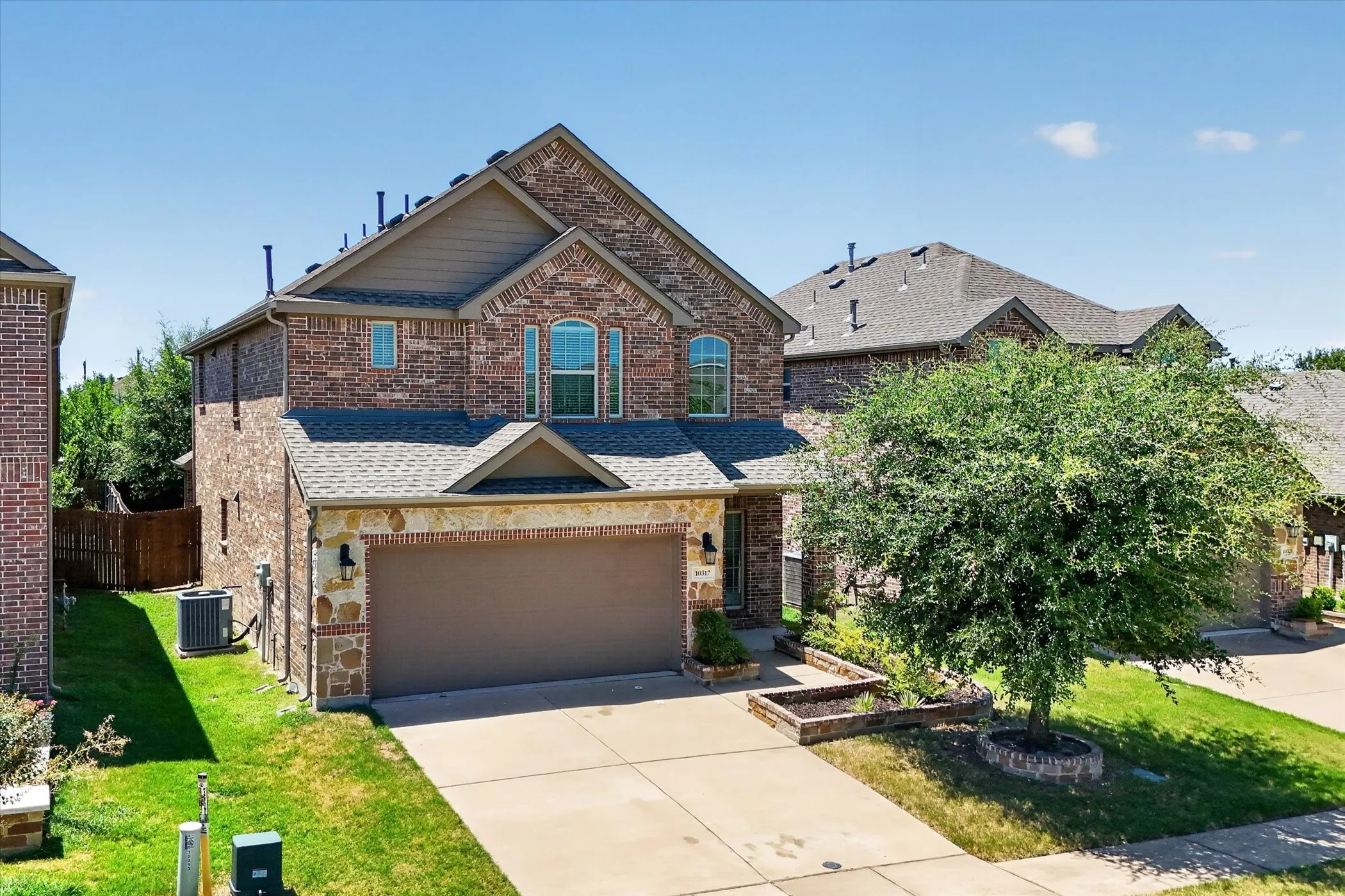 Brick and stone exterior featuring an attached two-car garage with a brown door