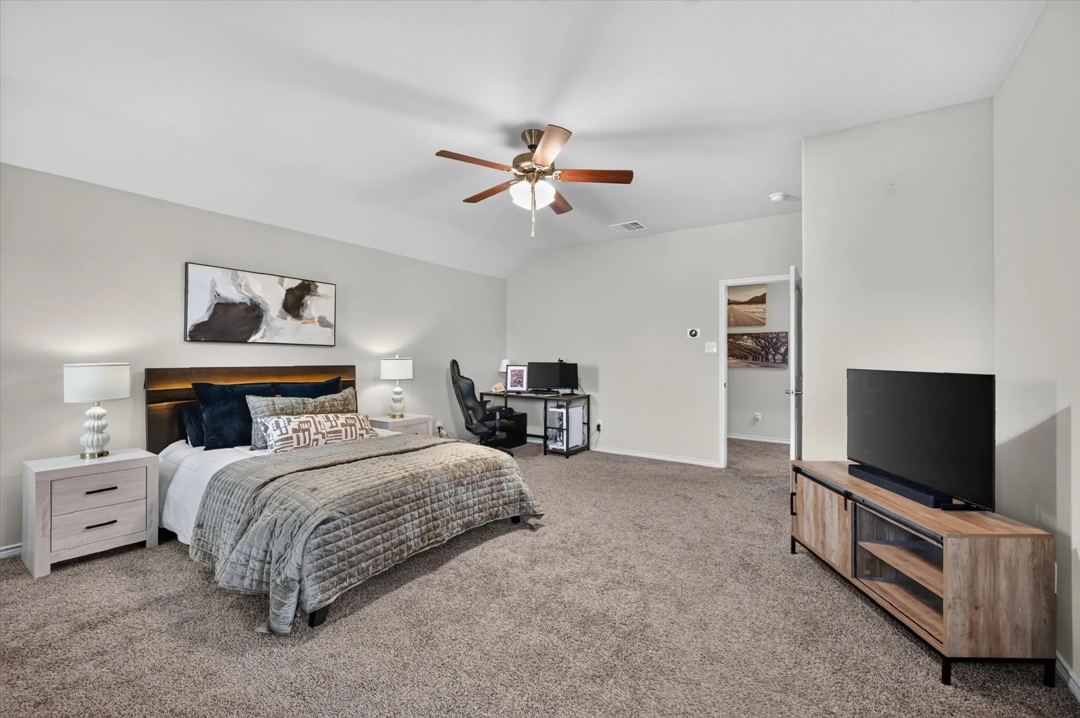Spacious bedroom featuring vaulted ceilings, neutral-toned walls, and plush carpet flooring