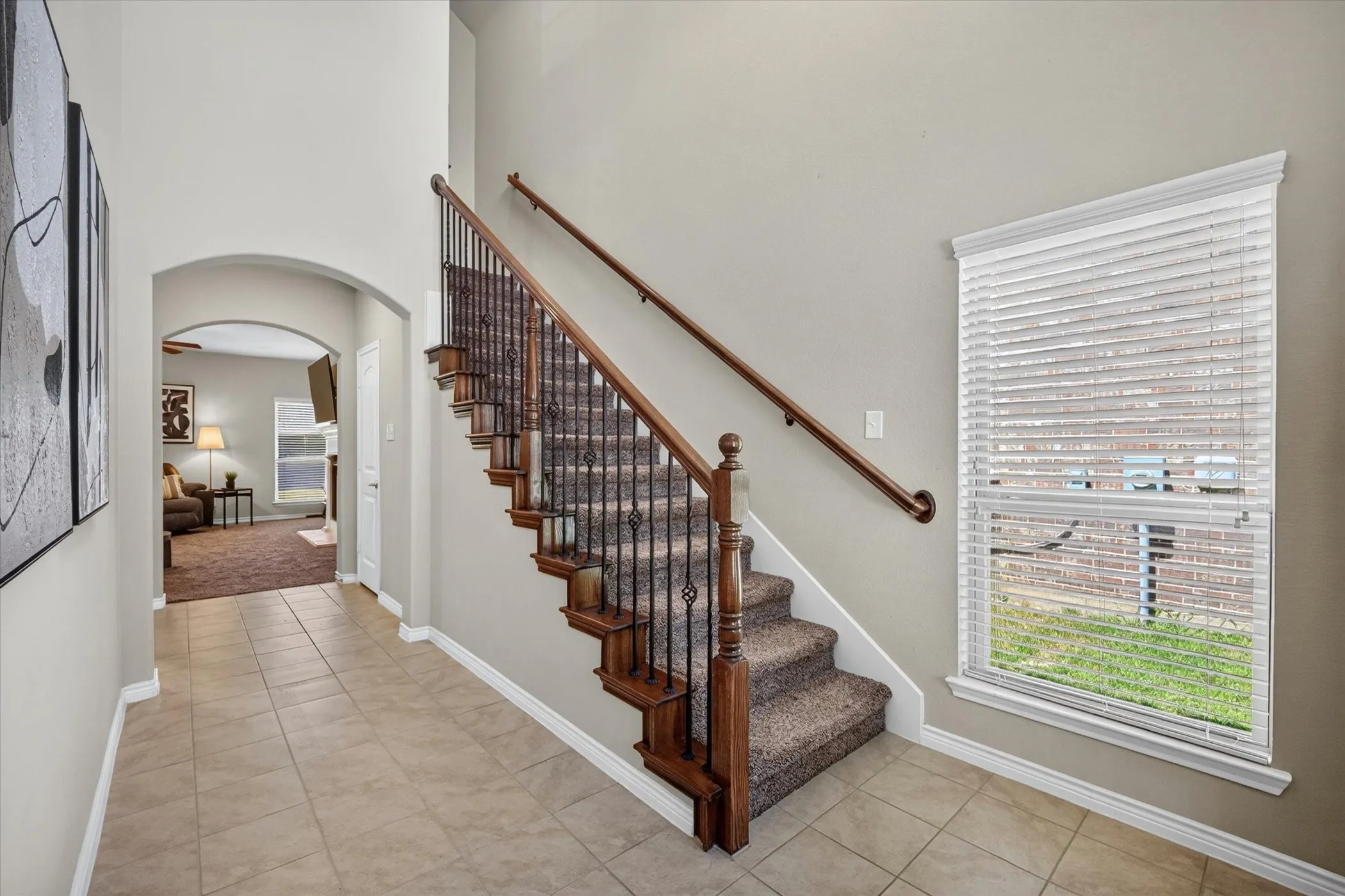 Entryway featuring a grand staircase with dark wood newel posts and wrought iron balusters
