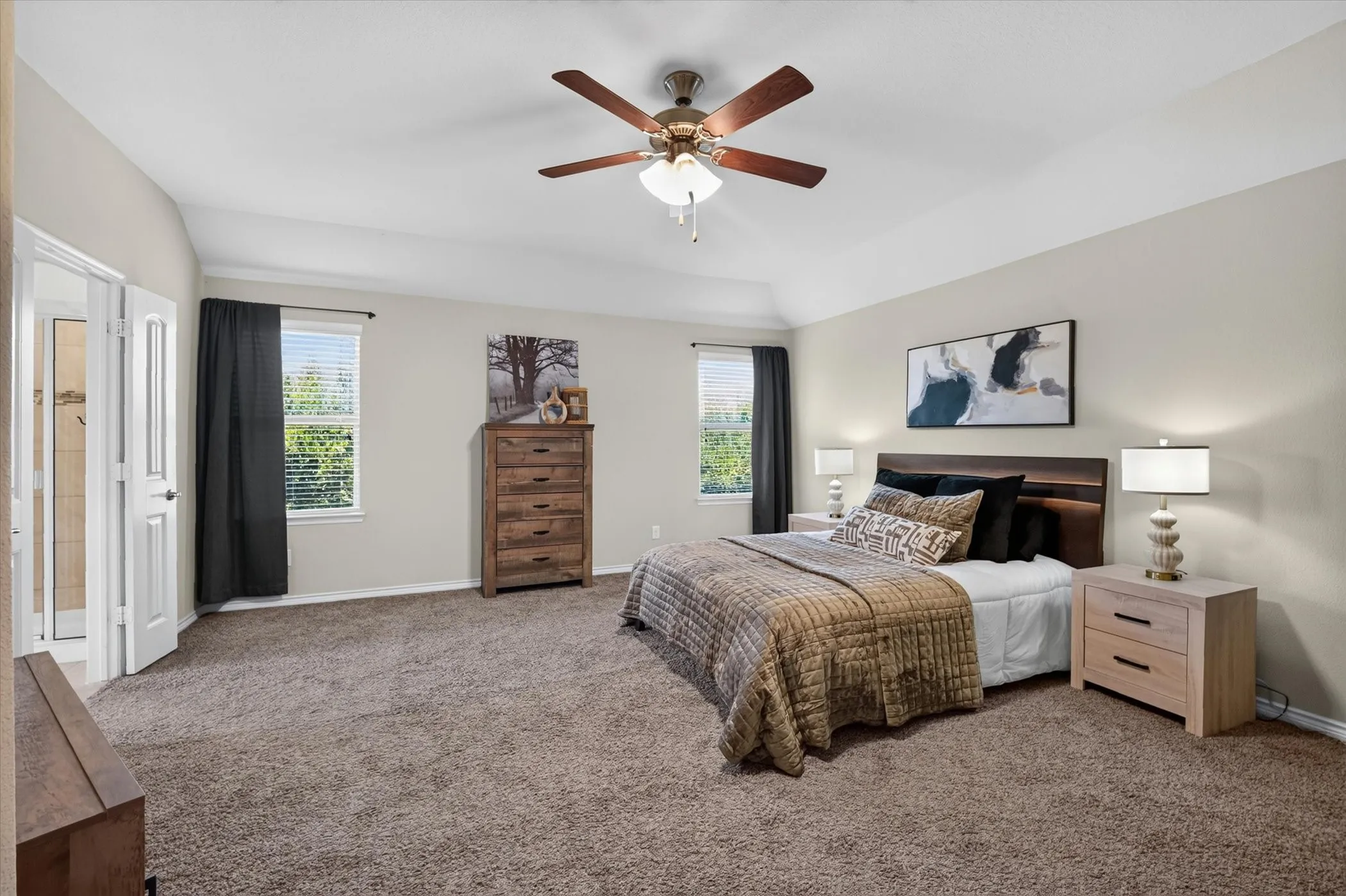 Spacious room featuring vaulted ceilings, a ceiling fan with integrated lighting, and carpeted flooring