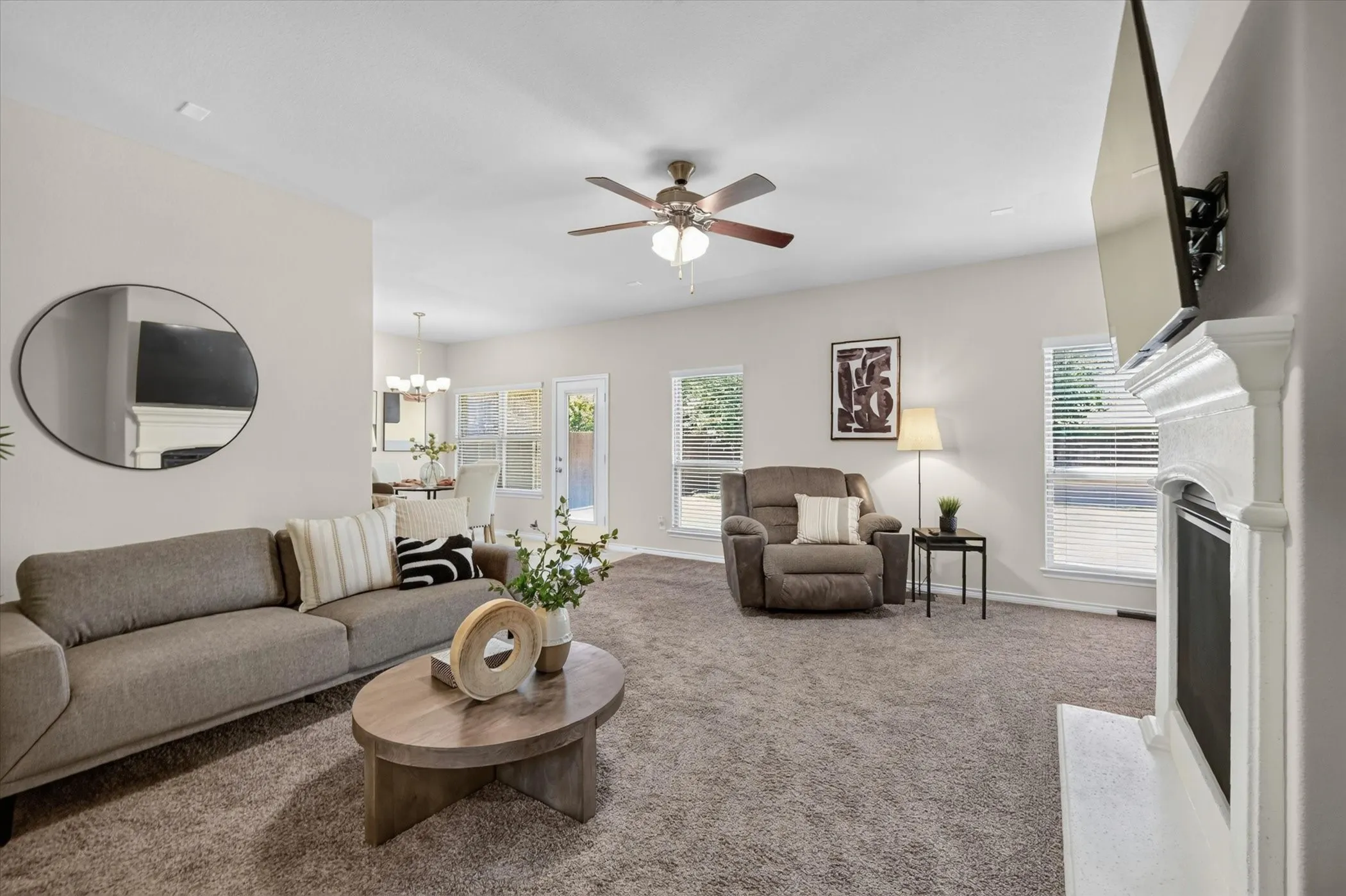 Spacious living area featuring neutral carpeting and a fireplace with a white mantel