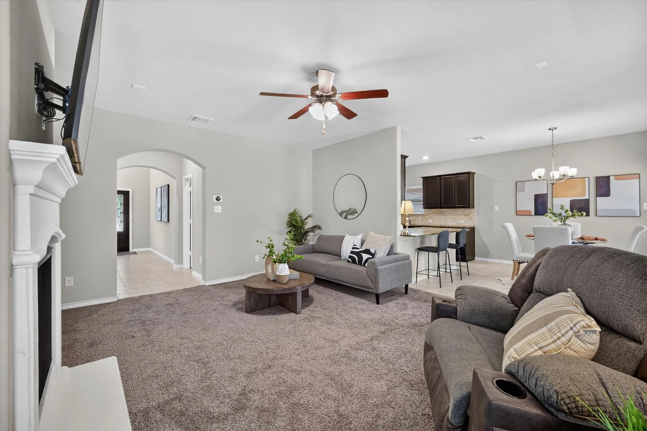 Spacious living area featuring carpet flooring and a ceiling fan