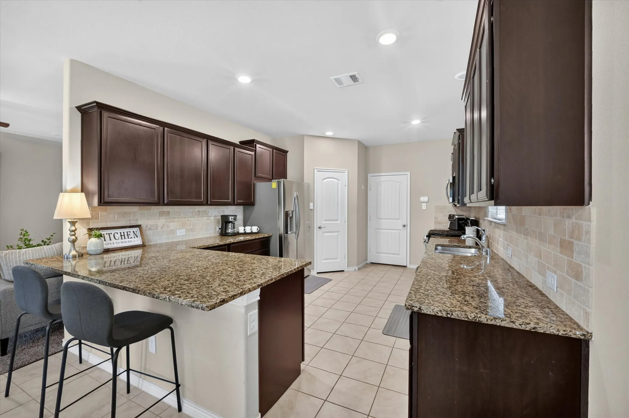 Kitchen featuring extensive dark wood cabinetry, granite countertops, stainless steel appliances, and a tiled backsplash