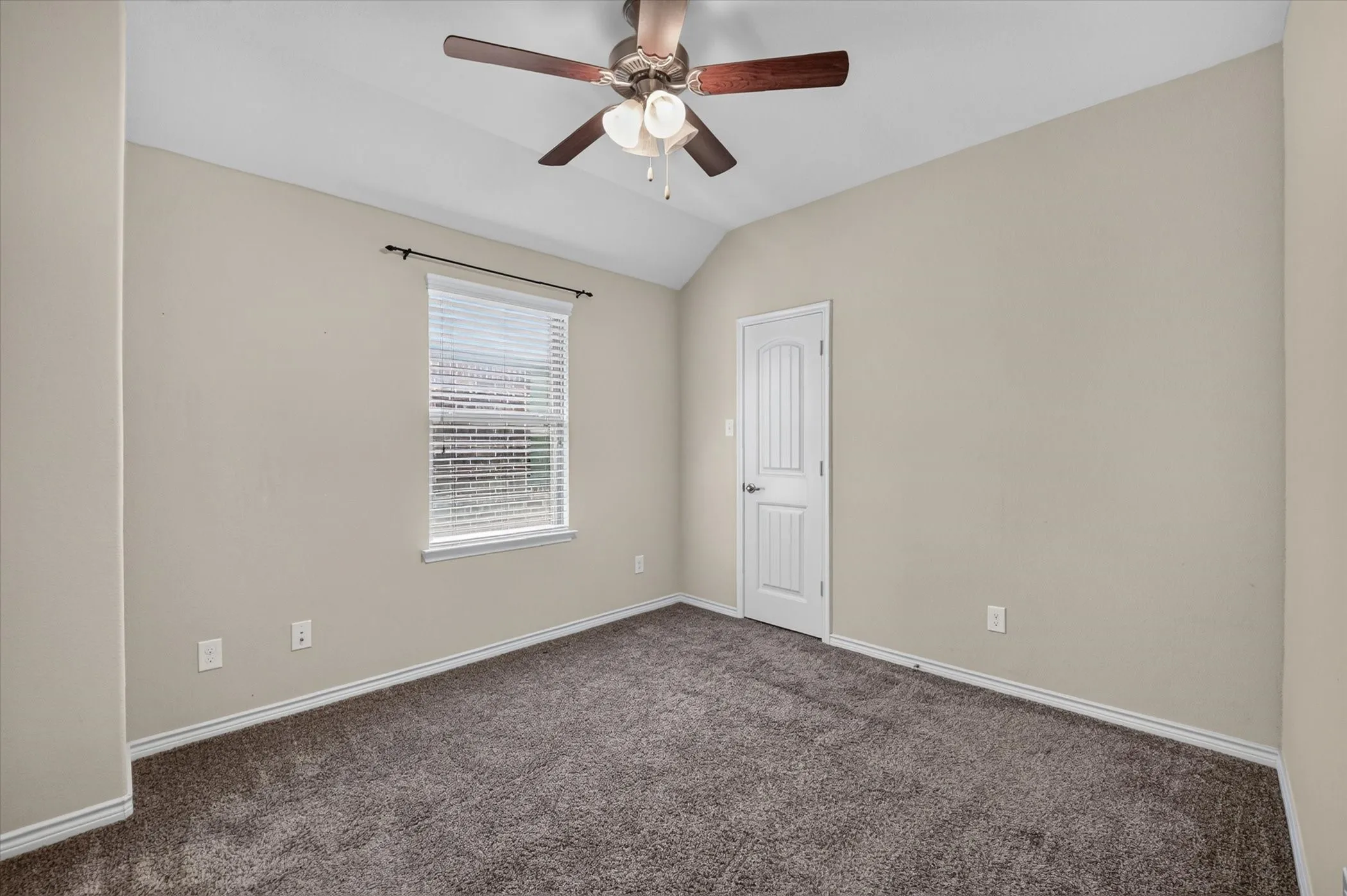 Carpeted room featuring a vaulted ceiling and ceiling fan with integrated lighting