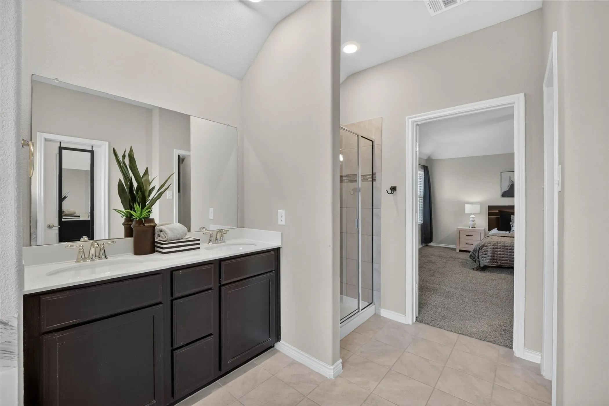 Bathroom featuring a dual vanity with dark wood-finish cabinetry and white countertops